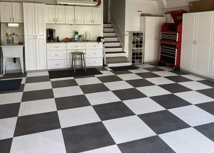 This may contain: a checkered floor in a garage with white cabinets and black and white tiles on the floor