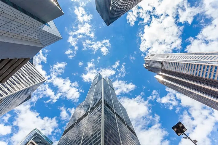 This may contain: looking up at skyscrapers from the ground with blue sky and clouds in the background