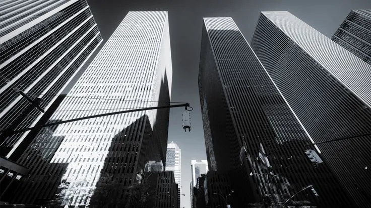 This may contain: black and white photograph of skyscrapers in new york city, ny with street light