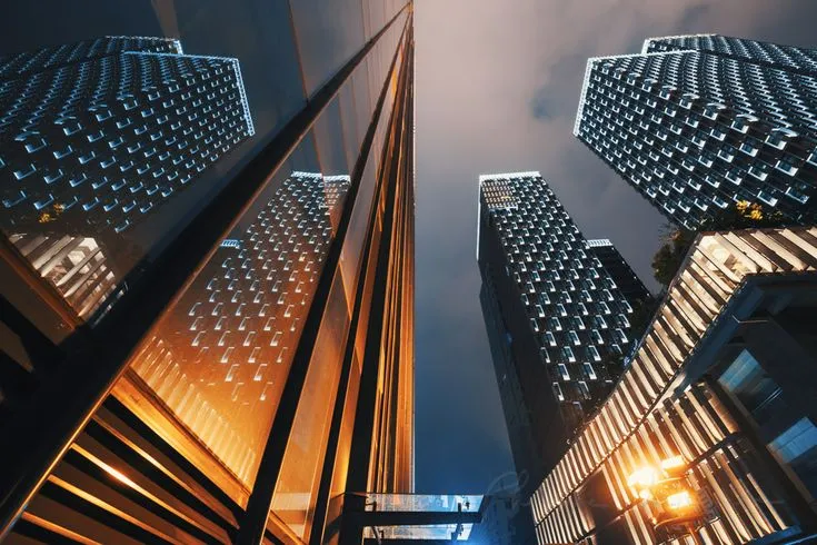 This may contain: looking up at skyscrapers in the city from below, with lights shining on them