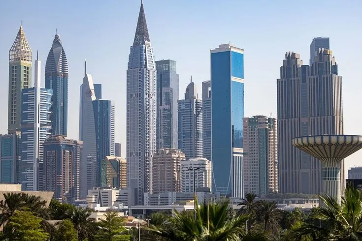 This may contain: there are many tall buildings in the city with palm trees on the foreground and blue sky behind them