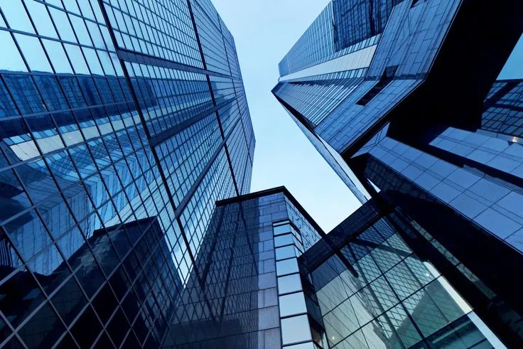This may contain: several tall buildings with glass windows in the middle and one is blue, while the other two are black