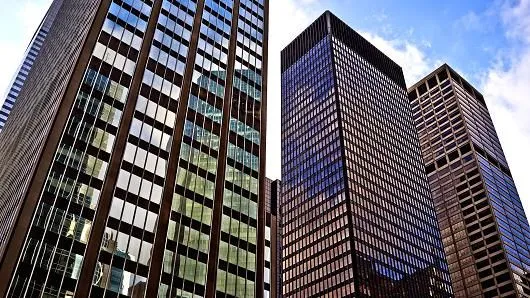 This may contain: three skyscrapers are shown against a blue sky with some clouds in the back ground