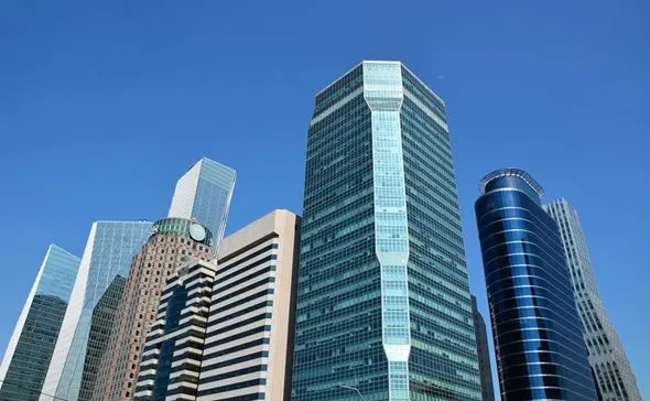 This may contain: several tall buildings in the city against a blue sky
