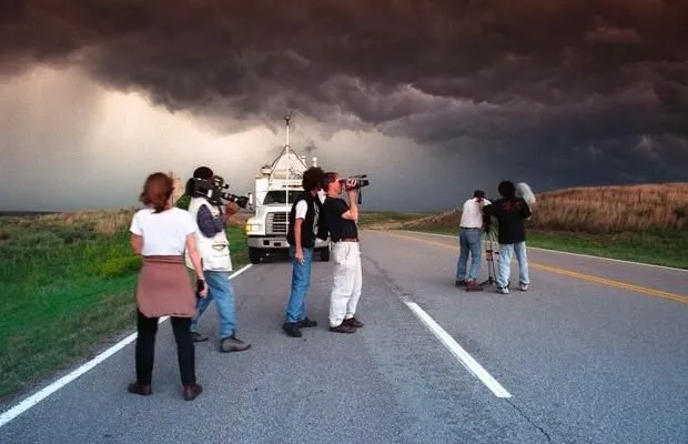 This may contain: a group of people standing on the side of a road with a truck in the background