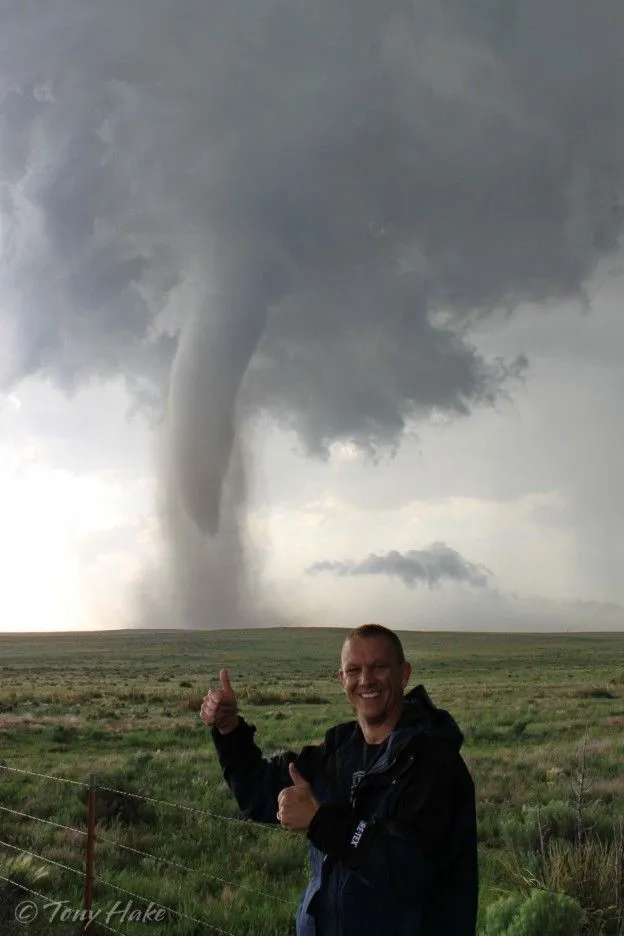 This may contain: a man is giving the thumbs up in front of a large cloud that looks like a tornado