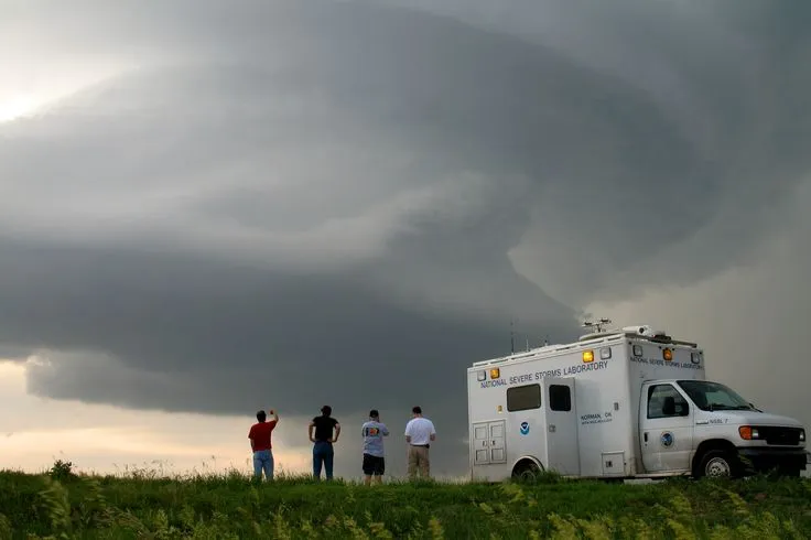 This may contain: three people standing in front of an ambulance under a storm cloud