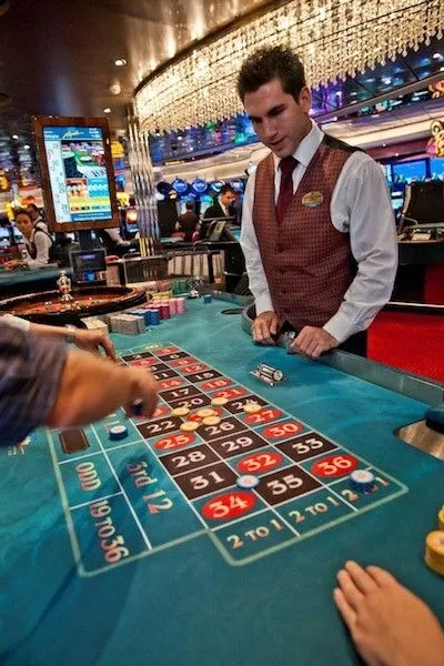 This may contain: a man playing roulejack in a casino with other people looking at the table
