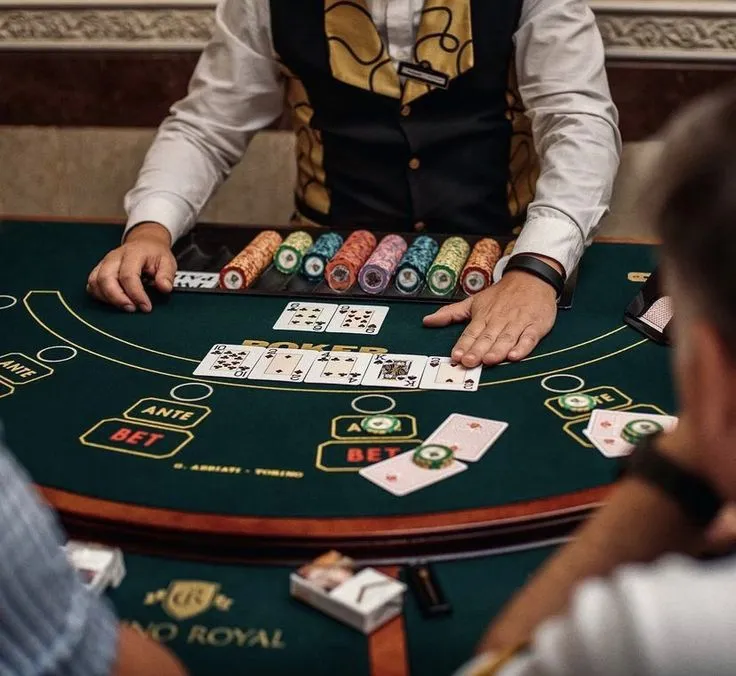This may contain: a man sitting at a blackjack table in front of two other men playing cards