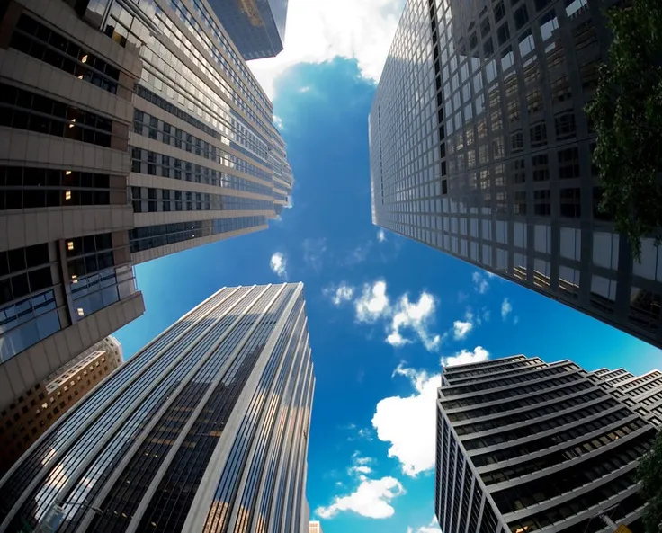 This may contain: looking up at skyscrapers from the ground to the sky with clouds in the background
