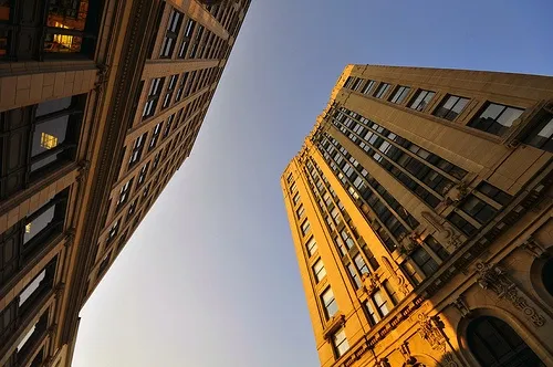 This may contain: looking up at two tall buildings in the city, one is yellow and the other is brown