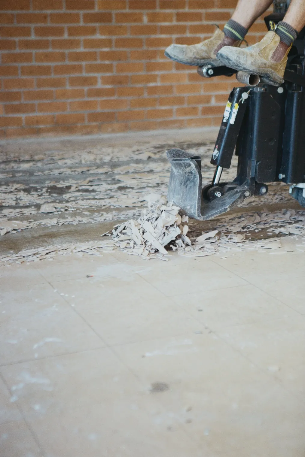 Contractor removing floor covering with ride on floor scraper