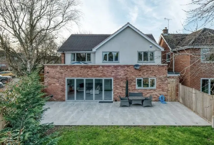 This may contain: a large brick house with a patio in the front and side yard area next to it