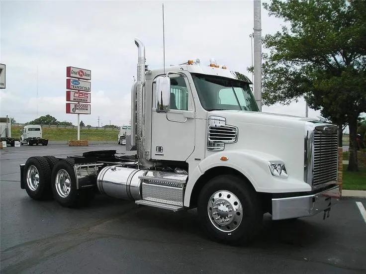 This may contain: a white semi truck parked in a parking lot next to a gas station and sign