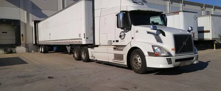 This may contain: a white semi truck parked in front of a building