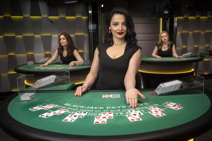 This may contain: three women sitting at a blackjack table with cards in front of them and one woman standing behind the table
