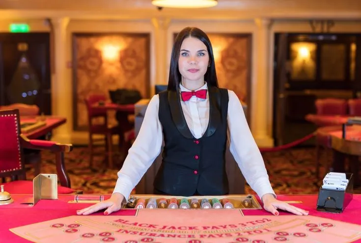 This may contain: a woman in a vest and bow tie standing next to a table with cards on it
