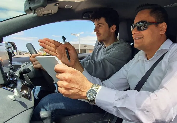 This may contain: two men are sitting in the driver's seat of a car and one is holding an electronic device