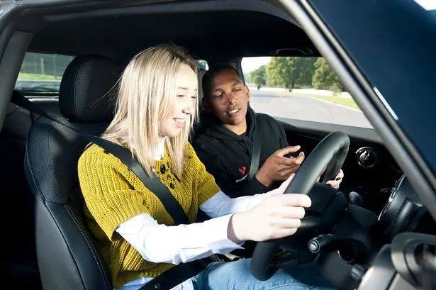 This may contain: a man and woman sitting in the driver's seat of a car looking at their cell phones