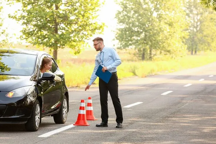 This may contain: a man standing next to a black car and orange cones on the side of the road