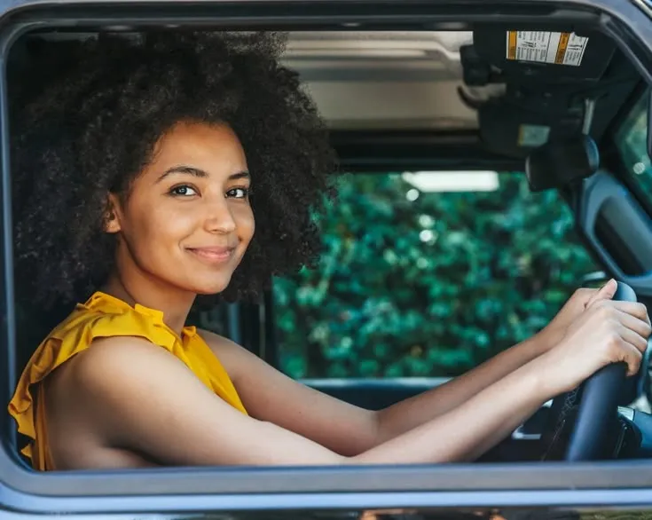 This may contain: a woman sitting in the driver's seat of a car