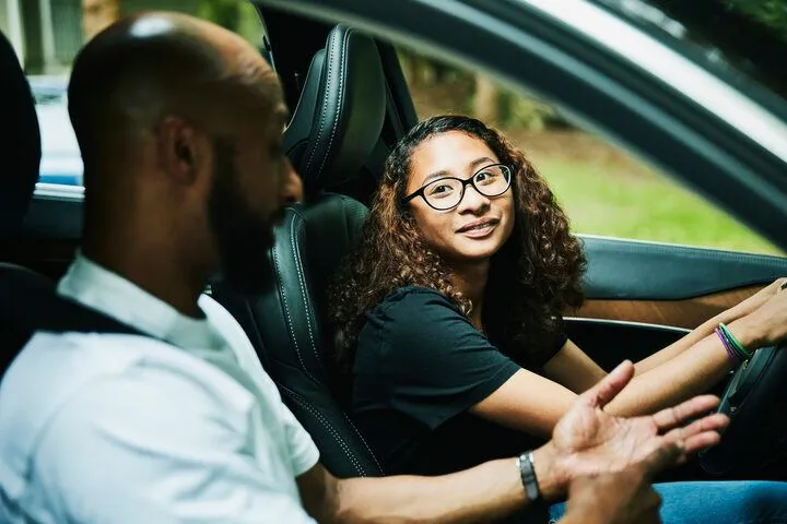 This may contain: a woman sitting in the driver's seat of a car talking to a man