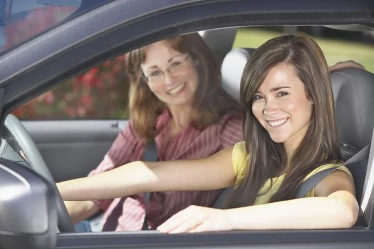 This may contain: two women sitting in the drivers seat of a car, one smiling at the camera