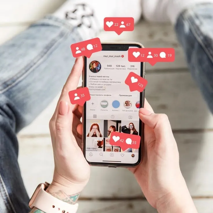 This may contain: someone is holding up their phone with red hearts on the screen and social media icons above them