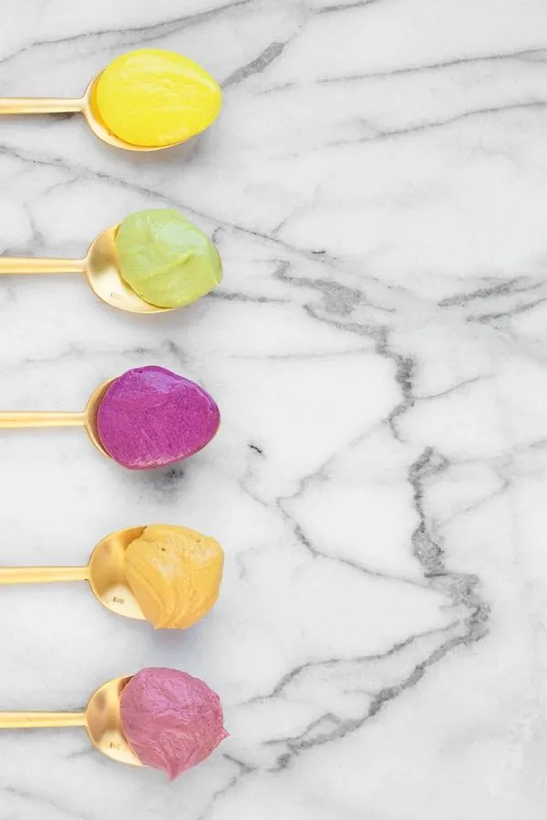 This may contain: four spoons with different colors on them sitting next to each other in front of a marble surface