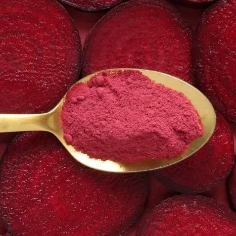This may contain: a spoon filled with red powder on top of beets