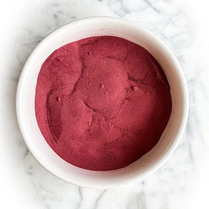 This may contain: a white bowl filled with red colored powder