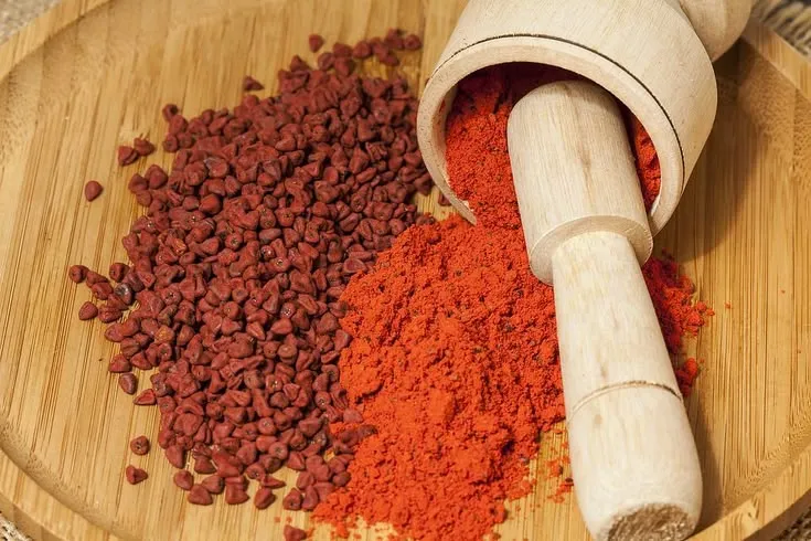 This may contain: a wooden bowl filled with lots of red food next to a mortar and pepper shaker