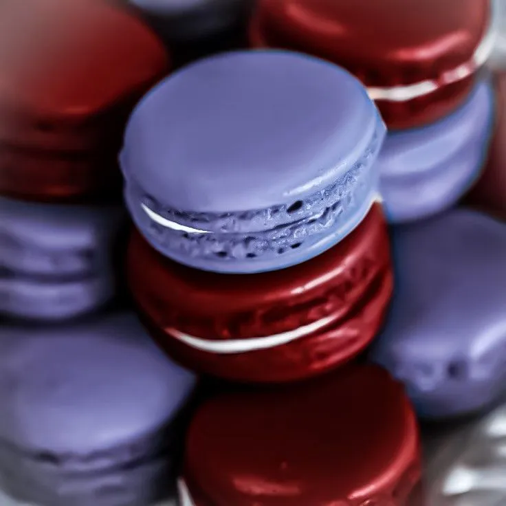 This may contain: several macaroons are stacked on top of each other with purple and red frosting