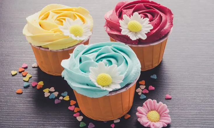 This may contain: three cupcakes decorated with colorful frosting and flowers