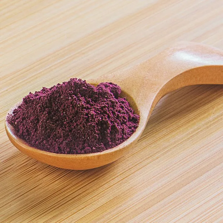 This may contain: a wooden spoon filled with purple powder