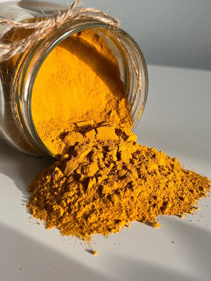 This may contain: a jar filled with yellow colored powder next to a pile of brown stuff on a white surface