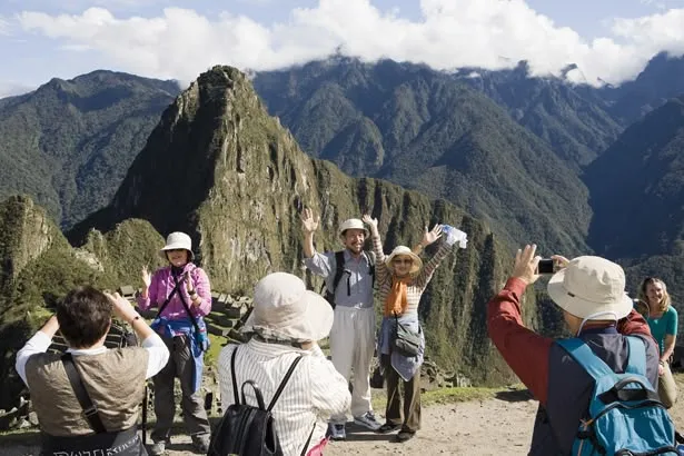 This may contain: people standing on top of a mountain with their hands in the air and mountains behind them