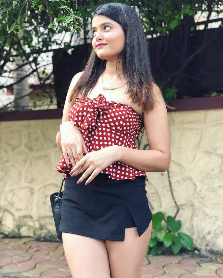 This may contain: a woman in short black shorts and a polka dot top is posing for the camera