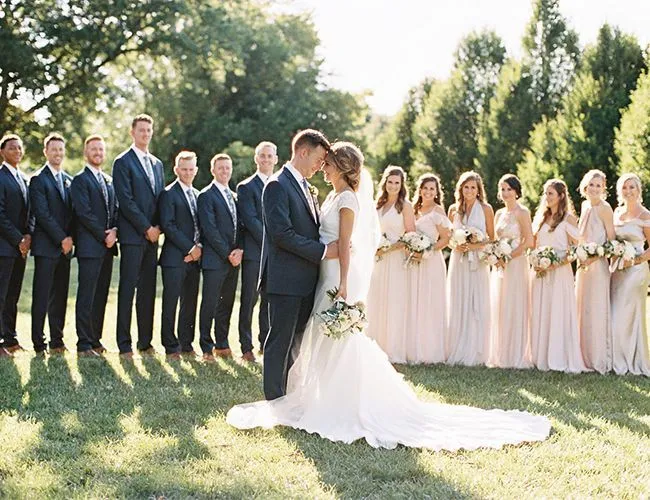 This may contain: a bride and groom kissing in front of their wedding party