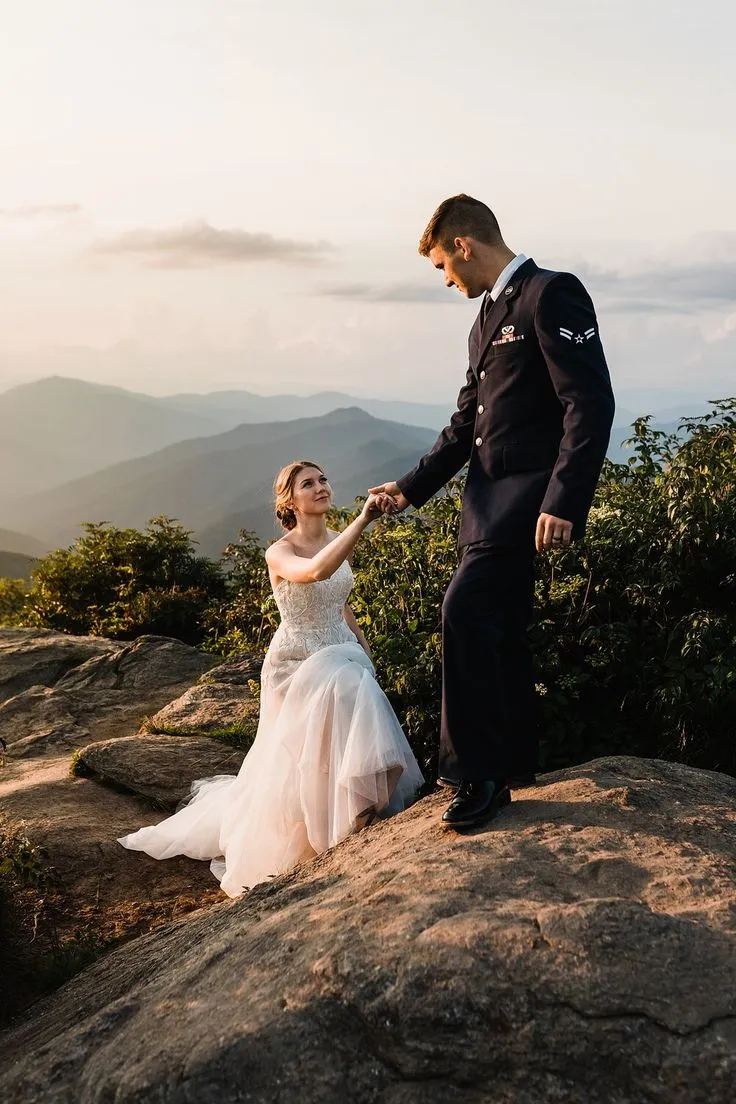 This may contain: a bride and groom holding hands on top of a mountain