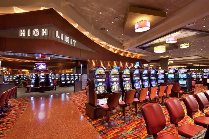 This may contain: a casino room filled with lots of red chairs and slot machine machines in front of them