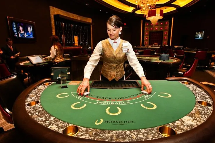 This may contain: a man standing in front of a blackjack table at a casino with people sitting around it