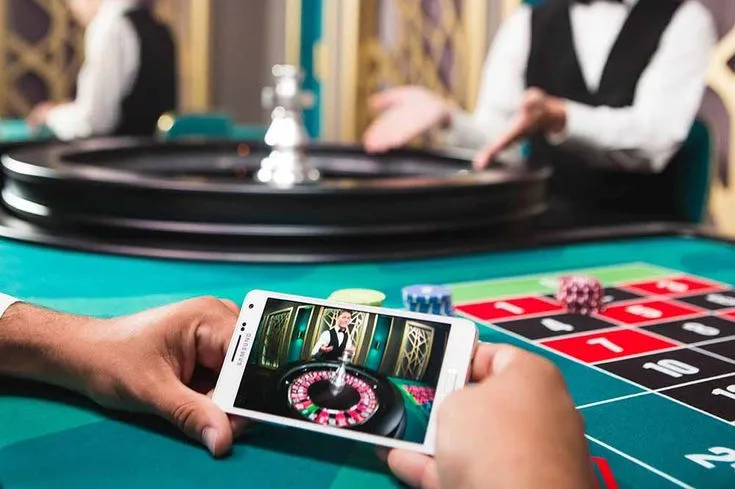This may contain: a person playing roulend on their cell phone at a casino table with other people in the background