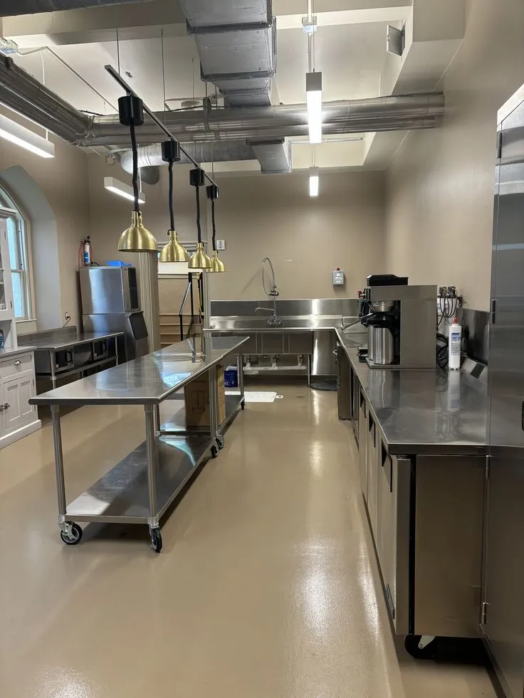 This may contain: an empty commercial kitchen with stainless steel counters and appliances on each side of the counter