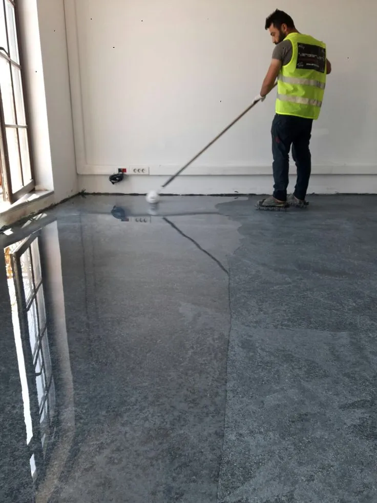 This may contain: a man with a mop is cleaning the floor in an empty room while wearing a safety vest