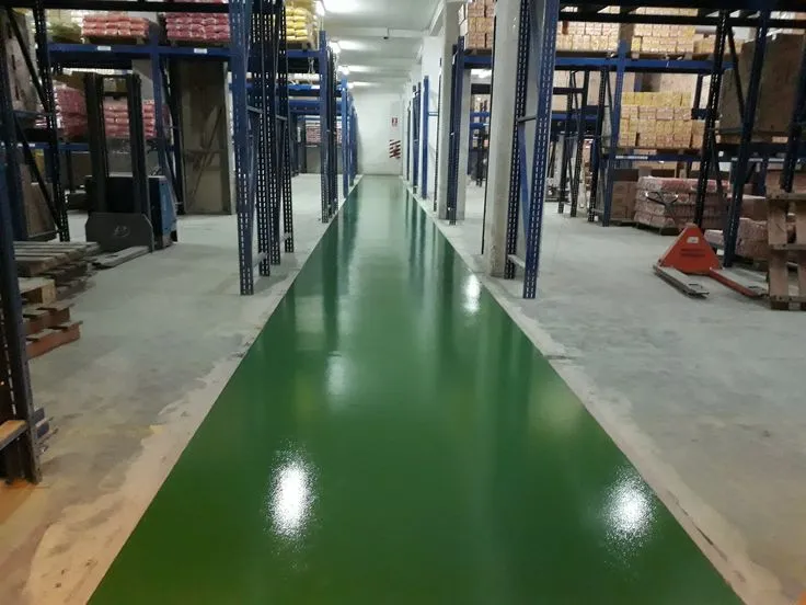 This may contain: an empty warehouse with green flooring and pallets on the sides, surrounded by blue metal shelving