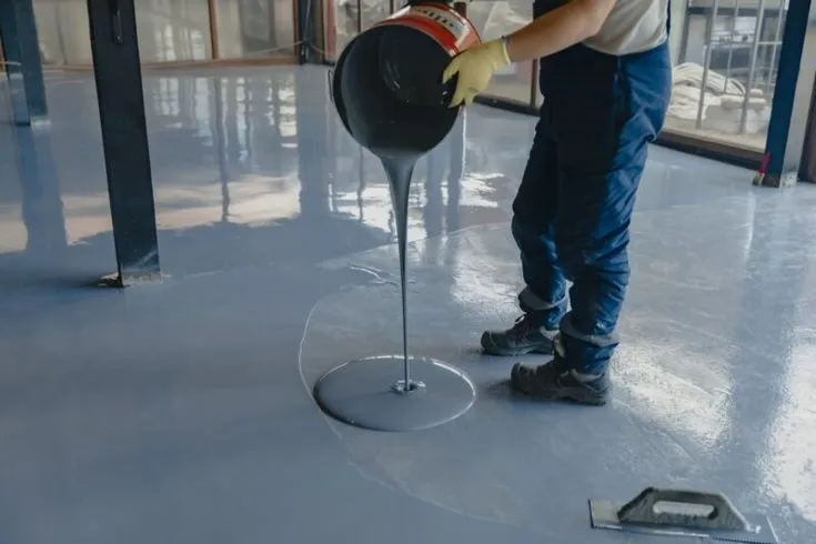 This may contain: a man in blue pants and yellow gloves cleaning a round object on a metal stand