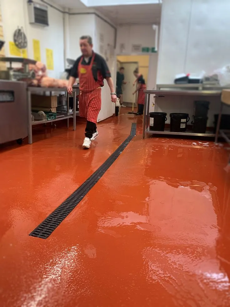 This may contain: a man in an orange apron is walking through a room with red flooring and white walls