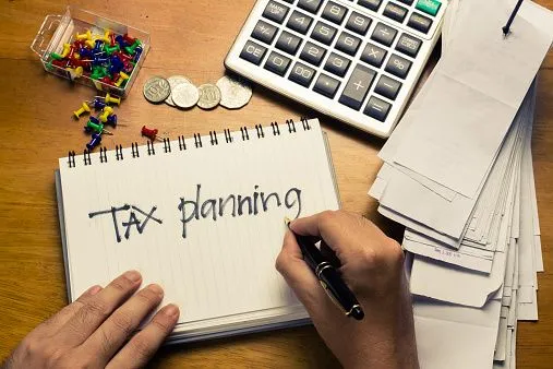 This may contain: a person writing tax planning on a notebook