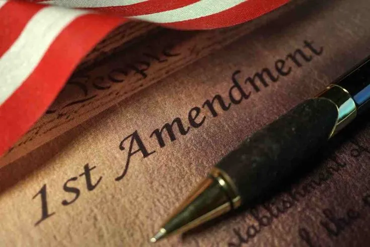 This may contain: a pen sitting on top of an american flag next to a paper with the word 1st amendment